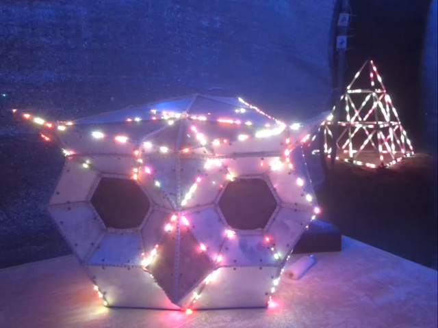 a polygonal owl on a table with a pyramid behind it. it starts with a glittery pattern in the owl and then switches to falling white particles.