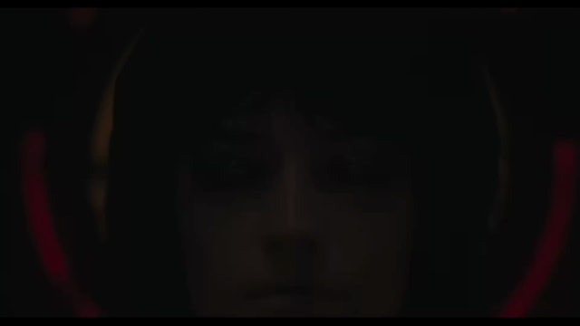 A fast zoom in on a beautiful woman who is being flooded with golden lights. When lit up she sparkles and glows. The camera pulls in very close to her eyes which are covered in glitter, they open.