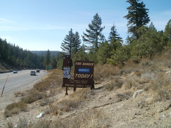 Smokey Bear sign in better days, bear wearing jeans and holding a shovel