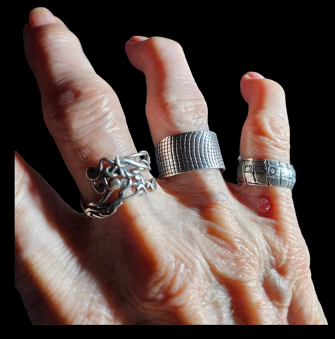 Photo of an elderly person's hand wearing handcrafted silver rings