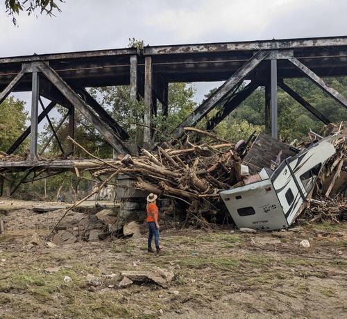 photo - USGS Hydrologic Technician Pamela Loftin looks on at the aftermath of severe flooding on Pigeon River in Newport, Tennessee. USGS crews were onsite October 1 to measure high-water marks to determine how high the flood waters reached at this location.
