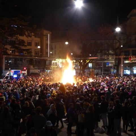 A wooden guy is burned in the middle of a crowd in the middle of Lausanne near the Flon metro station