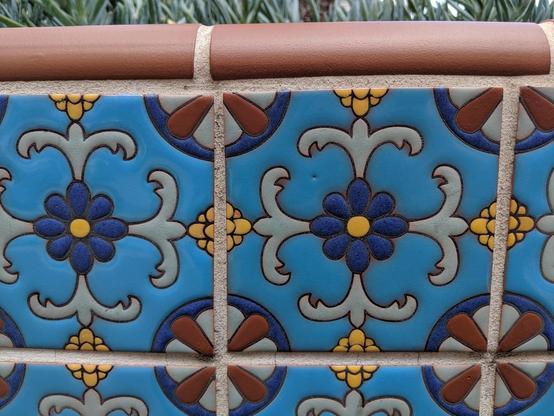 Alt Text: Image displays blue painted azulejo ceramic tile on a low wall surrounding a planted area in a courtyard.

Texte alternatif : L'image montre des carreaux de céramique azulejo peints en bleu sur un muret entourant une zone plantée dans une cour.

Texto alternativo: La imagen muestra azulejos de cerámica pintados de azul sobre un muro bajo que rodea un área plantada en un patio.