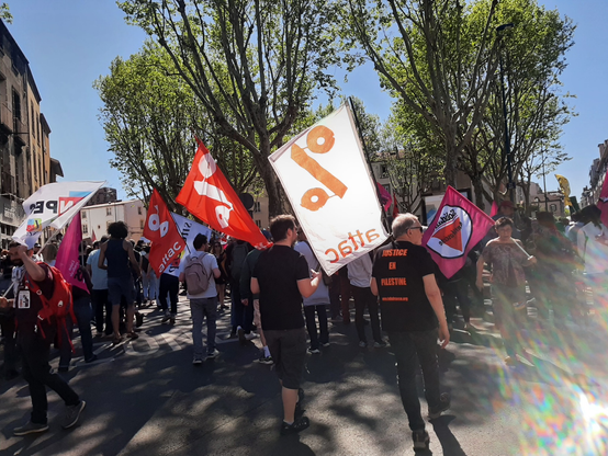 Photo de la manifestation du 1er mai 2025.
On voit 3 militant·es d'Attac avec des drapeaux.