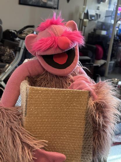 A pink ogre live hands puppet being boxed for shipping