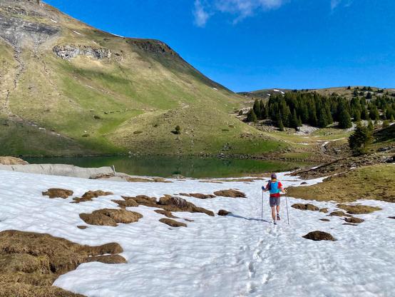 I’m trekking across the last patches of spring snow, the sun at my back and a mountain lake shimmering ahead. The contrast between the melting snow, the fresh green slopes, and the clear blue sky makes this moment feel magical—quiet, remote, just the way I like it.