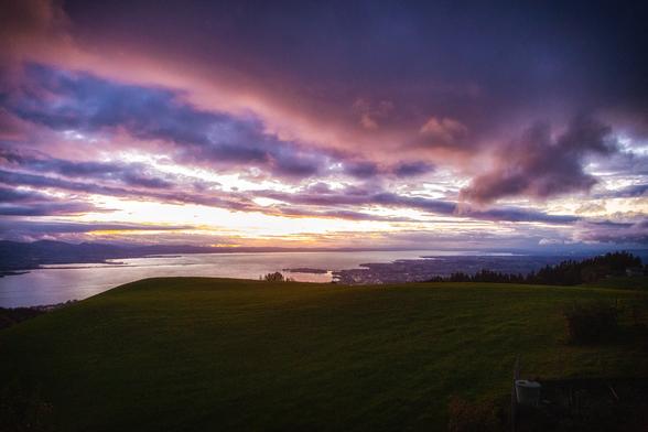 view from a hill over a large lake and dramatic purple and blue clouds
