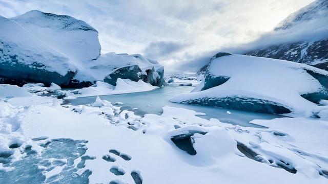 Massive turquoise ice chunks covered in snow litter an Alaska glacier field