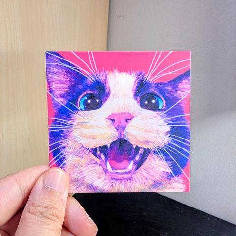 Photo of a left hand holding a square sticker. The sticker is a matte painting of a meowing cat.