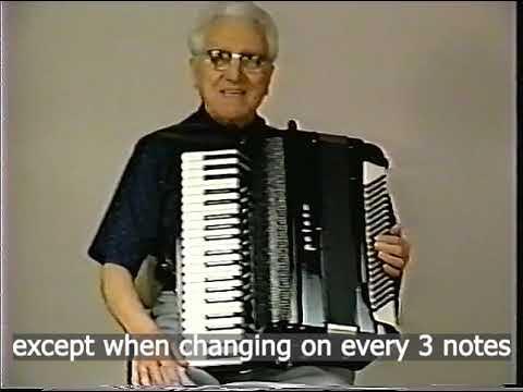 Still frame from a video of an older Gala-Rini with a full head of white hair now. Maybe age 70 or 80, but who could tell. Subtitle indicates it was an instructional video and this is only a fragment: “except when changing on every three notes”.