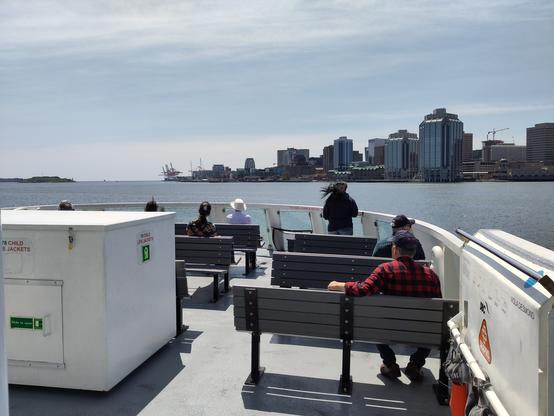 Foto. Aussendeck eines Schiffes, dahinter eine Skyline.