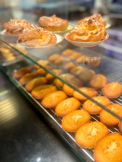A glass display case with golden madeleines and other fresh pastries.