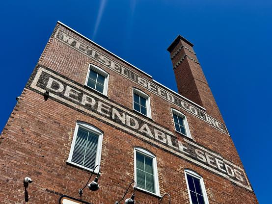 A brick building with “dependable seeds” painted on the wall in large capital letters.