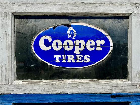 A weathered blue and white oval logo for Cooper Tires designed with the Cooper Black typeface.
