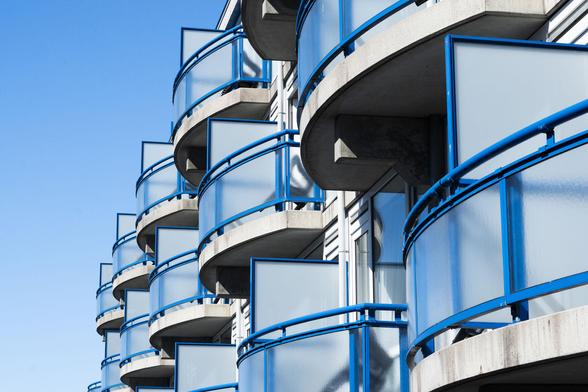 Photo of roundish balconies with blue railings, against a bright blue sky