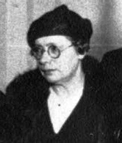 Celia Brañas in a dark beret style hat and round glasses