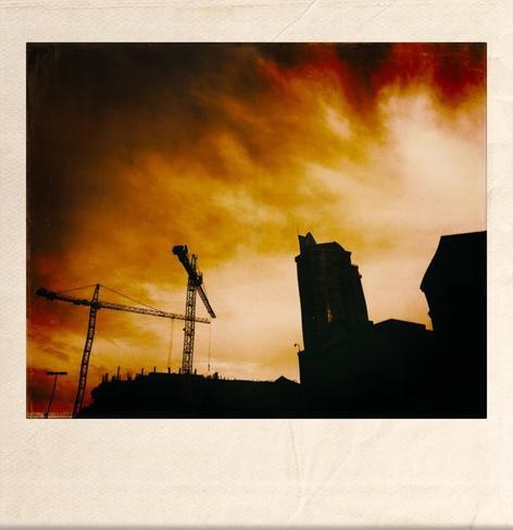 A color photo showing a view of an urban skyline against a dramatic orange sky.