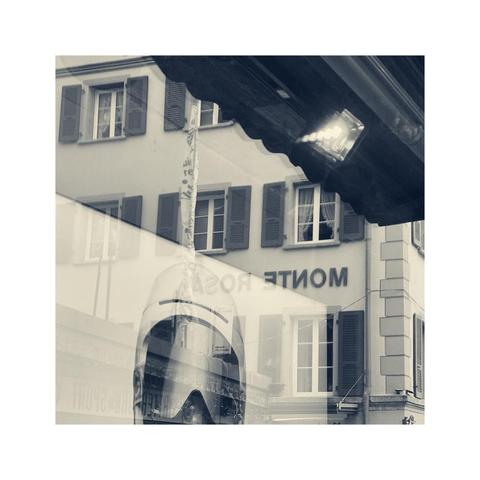 an angled view at a shopping window presenting ski googles. the mirrored title of a hotel named "monte rosa" can be identified. there's a bright reflection of a spotlight in the upper area