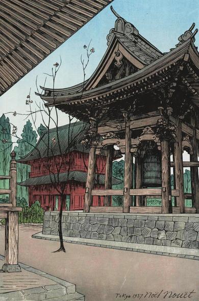 A view looking up at the temple bell at Ikegami Honmonji on a bright spring day. A single tree stands between us and the bell, a few pink blossoms clinging to its otherwise bare branches. The tall temple gate stands beyond, flanked by green trees; above, the sky is blue and cloudless.