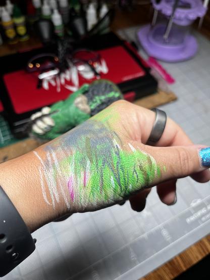 Side of the hand with multiple paint brush strokes in various colors