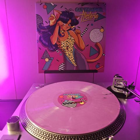 A purrple vinyl record sits on a turntable. Behind the turntable, a vinyl album outer sleeve is displayed. The front cover shows an anime cat girl dancing in an 80's style leotard.