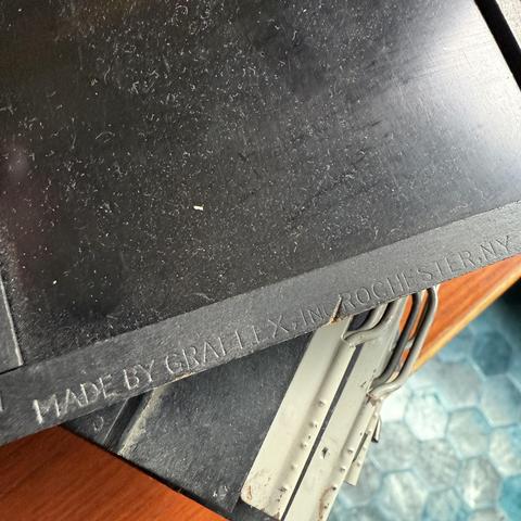 A close up detail of a vintage wooden film holder. The text embossed into the wooden edge of the holder reads:

Made by Graflex, Inc. Rochester, N.Y.