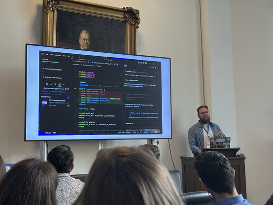 A person presenting on stage a screenshot of Cursor IDE
