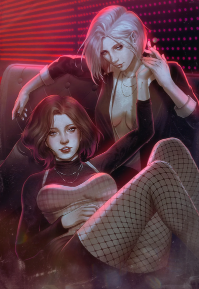 The image depicts two women sitting closely together on a couch in a dimly lit room with a red and pink neon background. The woman in the foreground has short, wavy brown hair and is wearing a black turtleneck with a plaid corset top and fishnet stockings. She is seated with her legs crossed and her hands resting on her lap. The woman in the background has short, platinum blonde hair and is wearing a black blazer over a low-cut top. She is leaning over the first woman, with her arm draped over the back of the couch. Both women are adorned with multiple necklaces, and the overall atmosphere is suggestive and intimate.