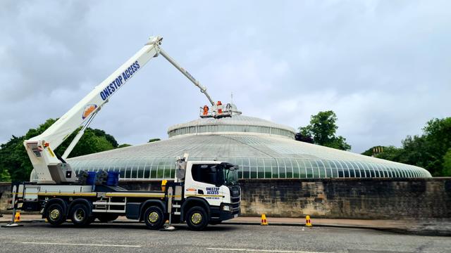 Using a cherry-picker to wash the glass in a large Victorian glasshouse.