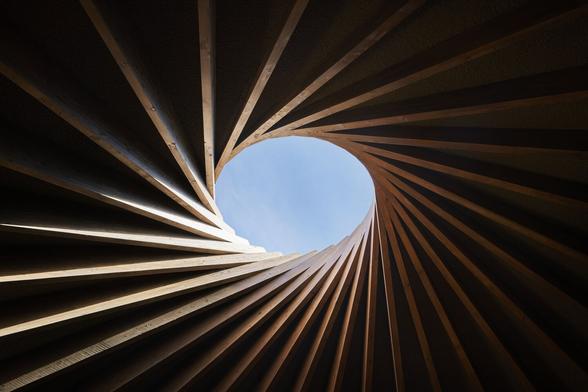 A wood spiral leading up to a hole in the ceiling.