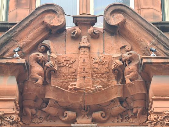 A pair of sculpted walruses holding up a cartouche featuring a lighthouse.