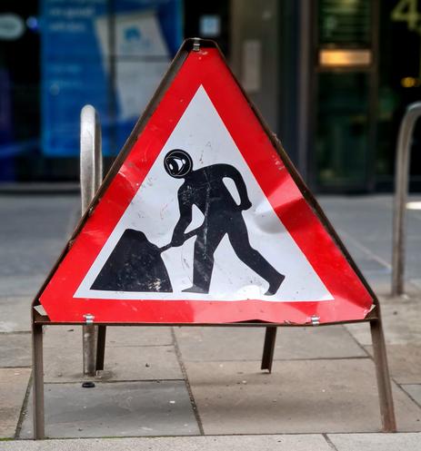 A men at work sign with a robot head sticker stuck over the head of the original man.