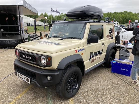 Beige Suzuki Jimny coffee truck with black plastic appendages and roof box, front quarter view
