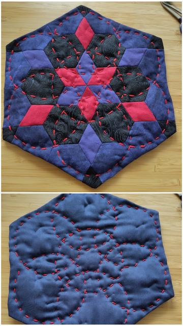 Zusammengesetztes Foto mit Vorder- und Rückseite eines kleinen sechseckigen Quilts. Die Vorderseite besteht aus roten, lilanen, blauen und schwarzen Sechsecken und Rauten. Die Rückseite ist eine Fläcke aus dunkelblauem Stoff. Beide Seiten sind mit roten Ziernähten in Kreismustern verquiltet.