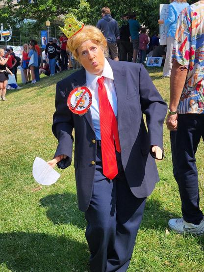Photo of a pretend DJT, in baggy blue suit and super long red tie. Weird orange hair.