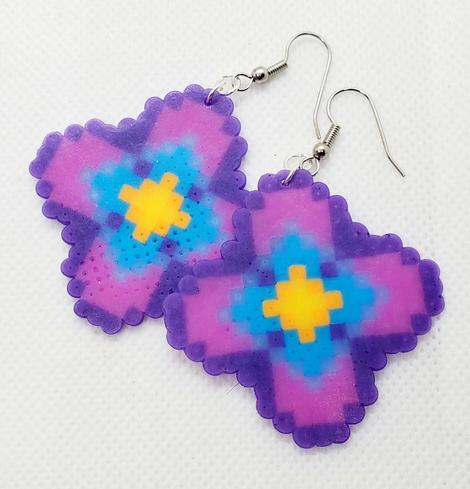 a pair of perler beaded earrings of a 4-petaled flower design made by kiamichi in pink and purple with bright blue and yellow centers