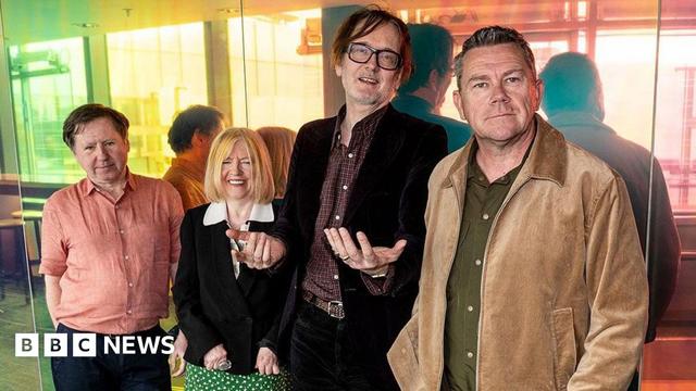 Pulp band seen on 10 April 2025 standing against a wall