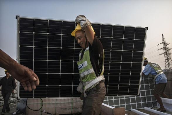 Ein Mann mit Bauhelm trägt ein Solarpanel