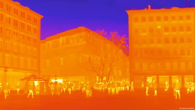 'Heat image' of a city square, with several buildings and a crowd of people, showing in orange and red where temperatures are the hottest 'Heat image' of a city square, with several buildings and a crowd of people, showing in orange and red where temperatures are the hottest