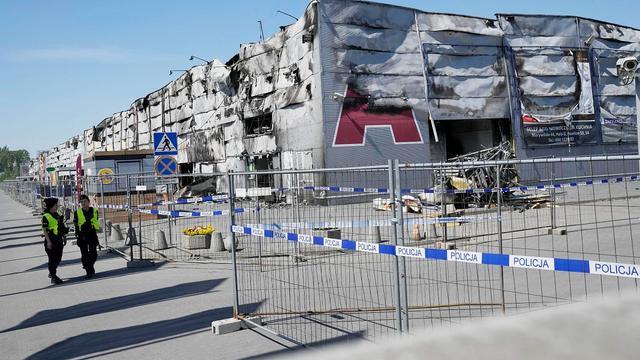 Police walks by a temporary fence put up to block access to a burnt-down shopping center in Warsaw, Poland, 15 May 2024. | Copyright AP Photo