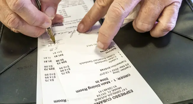 A person signing a credit card receipt.
