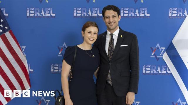 Yaron and Sarah standing infront of blue hoarding in between an US and Israeli flag