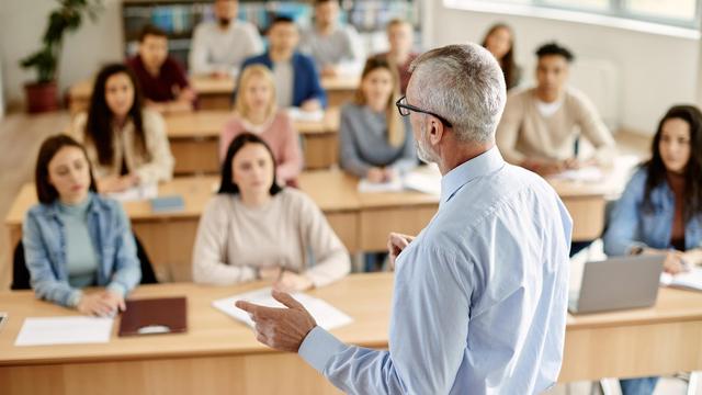 Un professeur vu de dos qui s'adresse à une classe.
