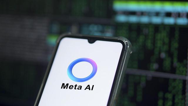 Auf einem Smartphone ist das Logo von Meta AI zu sehen: Ein überwiegend blauer Ring, der an manchen Stellen in Lila- und Grüntöne übergeht. 