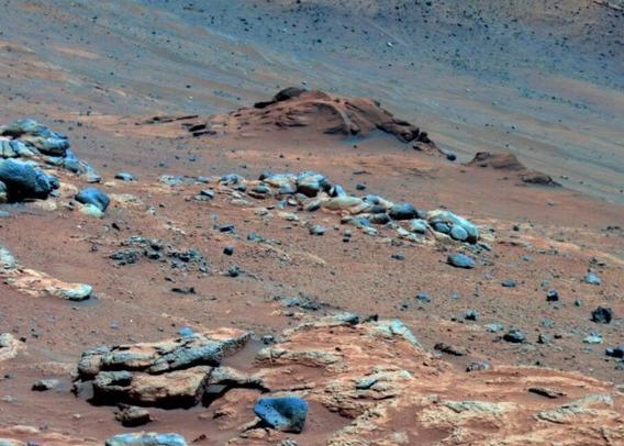 Image of a mix of rocks and dust, with the dust having a strong reddish tint.