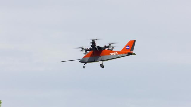 An orange-colored small aircraft flying in the air.