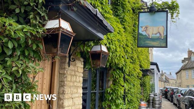 The Bull in Charlbury has a Cotswold stone exterior covered by green bushes - with the pubs sign hanging from it.