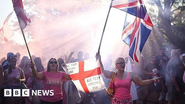A protest outside the Bell Hotel. Two women are holding St George and Union flags. On one flag is written the message: "Keep our children safe".