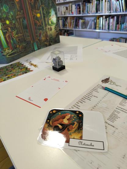 Photo d'une table avec une feuille de personnage et un écran de maître de jeu illustré par Florence Mangin 