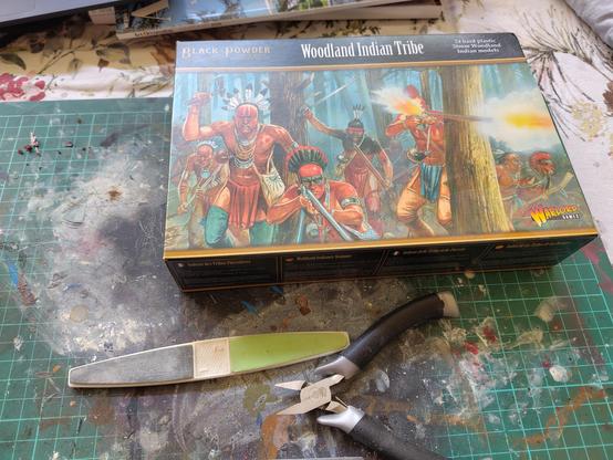 Boite de figurines et outils posé sur un tapis a maquette
